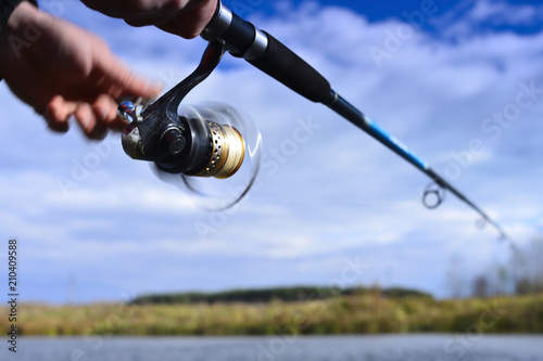 A fisherman catches a fish. Spinning reel closeup. Blurry.
