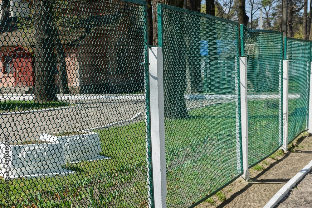 part of an iron fence made of green mesh on the street