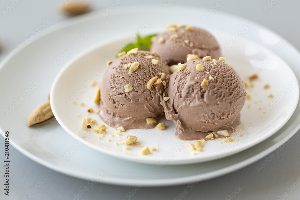Tasty homemade bowl of chocolate ice cream with mint and nuts on a light background. Tasty homemade bowl of chocolate ice cream with mint and nuts on a light background.