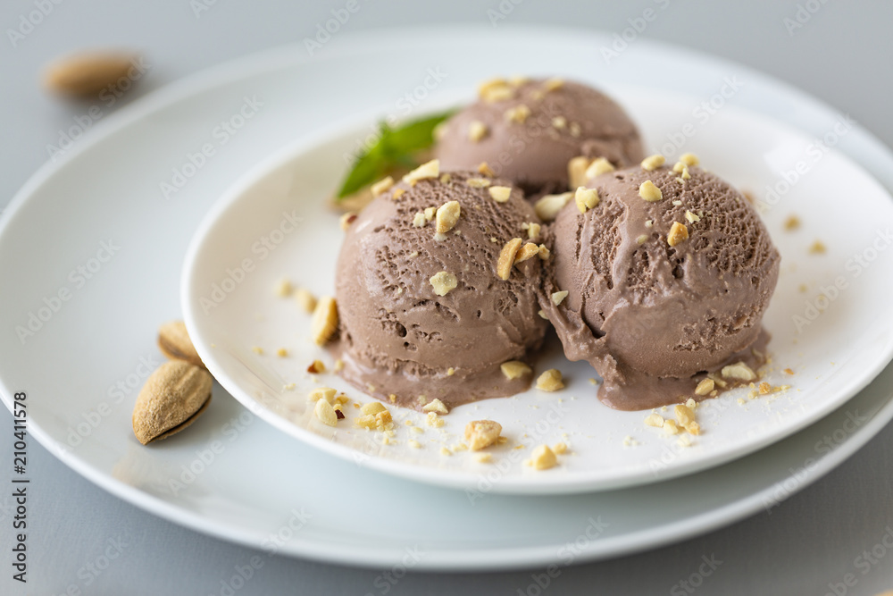 Tasty homemade bowl of chocolate ice cream with mint and nuts on a light background. Tasty homemade bowl of chocolate ice cream with mint and nuts on a light background.