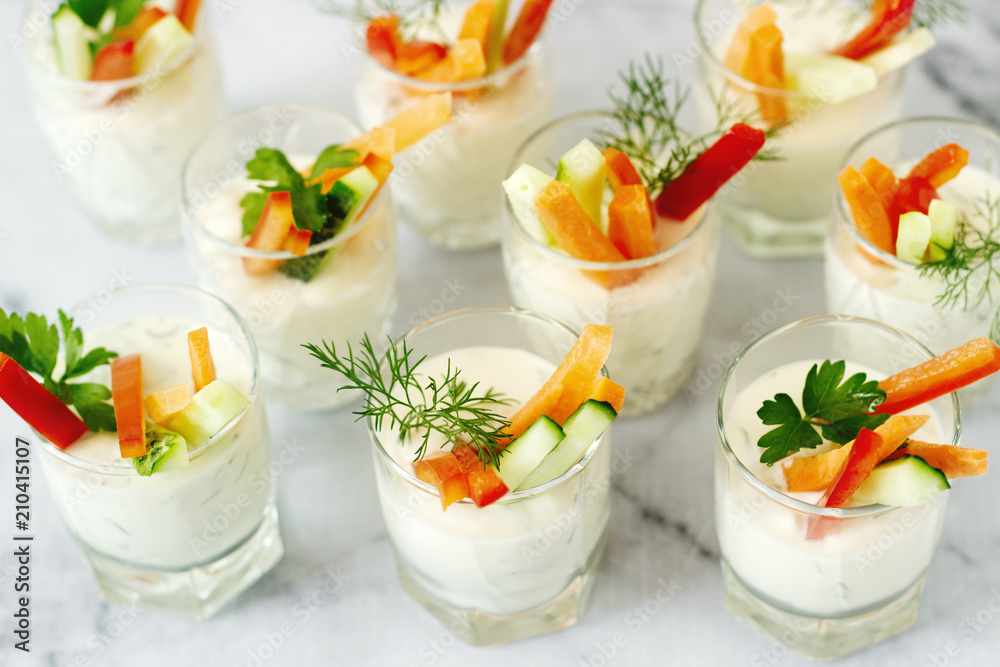 Snack in a glass with fresh cream and various vegetables on a light background. Snack in a glass with fresh cream and various vegetables on a light background.