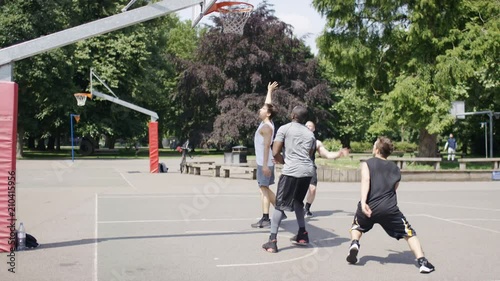 Group of young men playing basketball outdoors on a playground