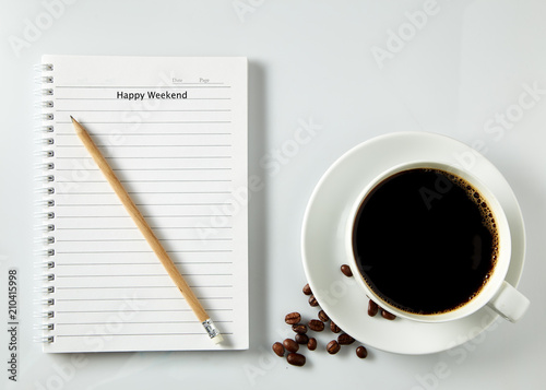 White cup of coffee morning on wooden table with notebook
