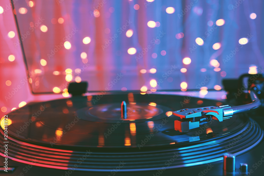 A vinyl record close-up on a dark background. Falling beam of light on a piece of vinyl. Turntable record player. Sound technology for DJ to mix & play music. Black vinyl record. Needle on the plate 