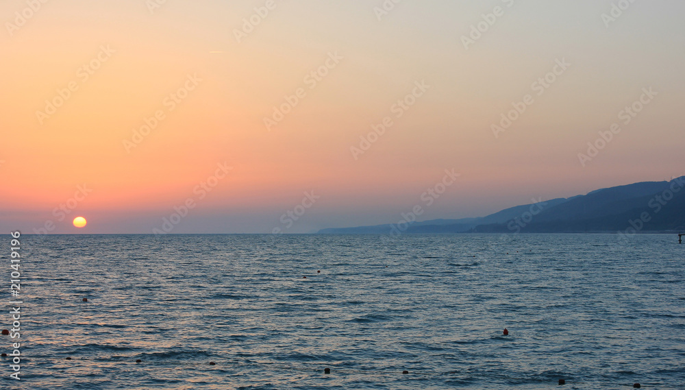 Sunset in the sea near the coastline and mountains