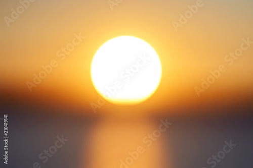 Blur big bright orange sunny disk at sunset of day in the sky close-up. Beautiful bokeh. Background for your ideas and design.