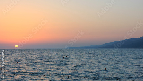 Sunset in the sea near the coastline and mountains