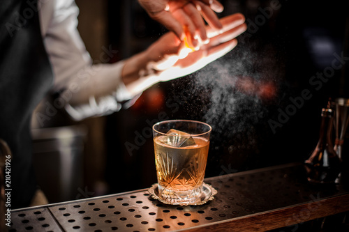 Bartender making a fresh summer old fashioned cocktail with orange juice