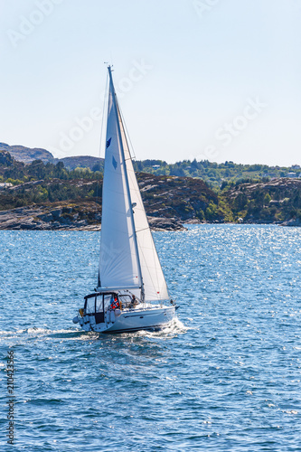 Sailboat at a rocky coastline at sea