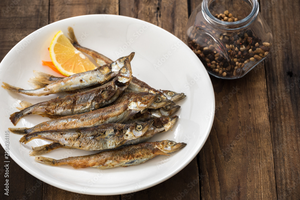 Grilled fish capelin or shishamo on white plate Grilled fish capelin or shishamo on white plate