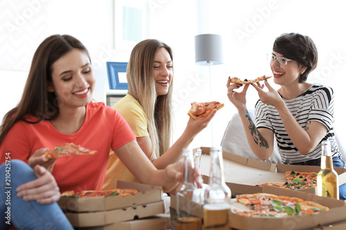 Young people having fun party with delicious pizza indoors