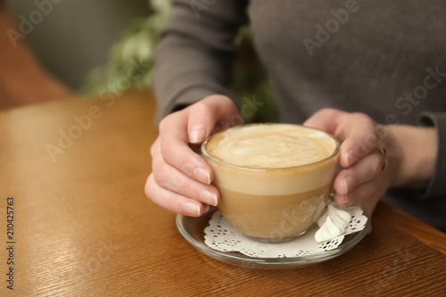 Young woman with cup of delicious coffee at table