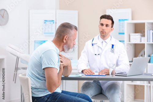 Coughing mature man visiting doctor at clinic