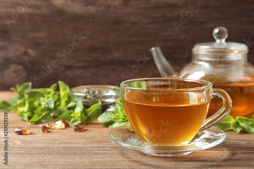 Cup with hot aromatic mint tea on wooden table