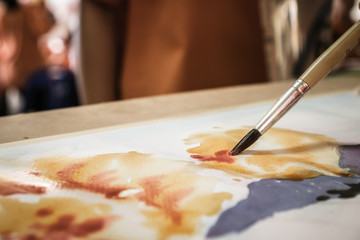 Student's hand with brush drawing on paper for creation picture abstract of watercolor painting with bamboo brush in Art subject classroom secondary education in Thailand