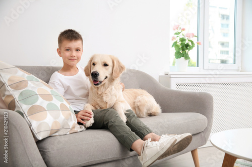 Cute little child with his pet on sofa at home