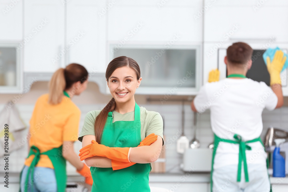 Obraz premium Team of professional janitors in uniform cleaning kitchen