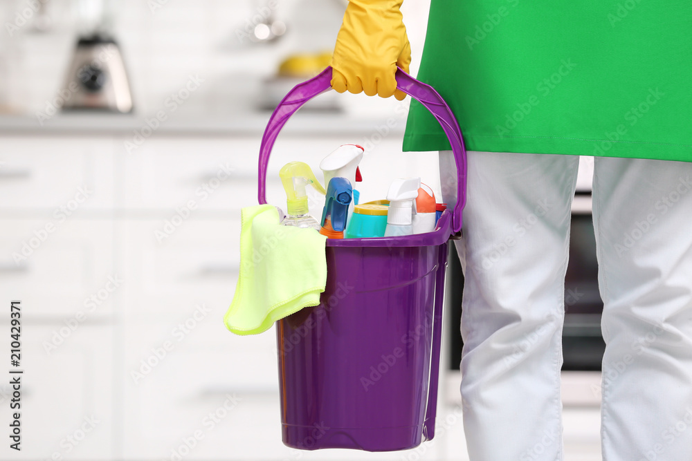 Man in uniform with cleaning supplies indoors Man in uniform with cleaning supplies indoors