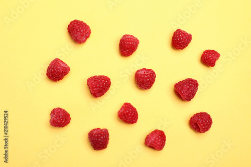 Flat lay composition with ripe aromatic raspberries on color background