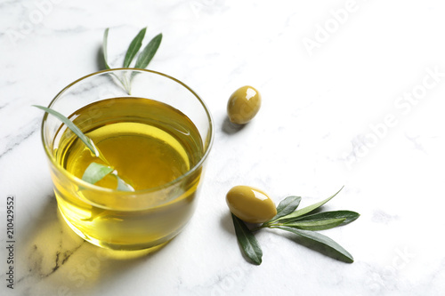 Glass with fresh olive oil on table