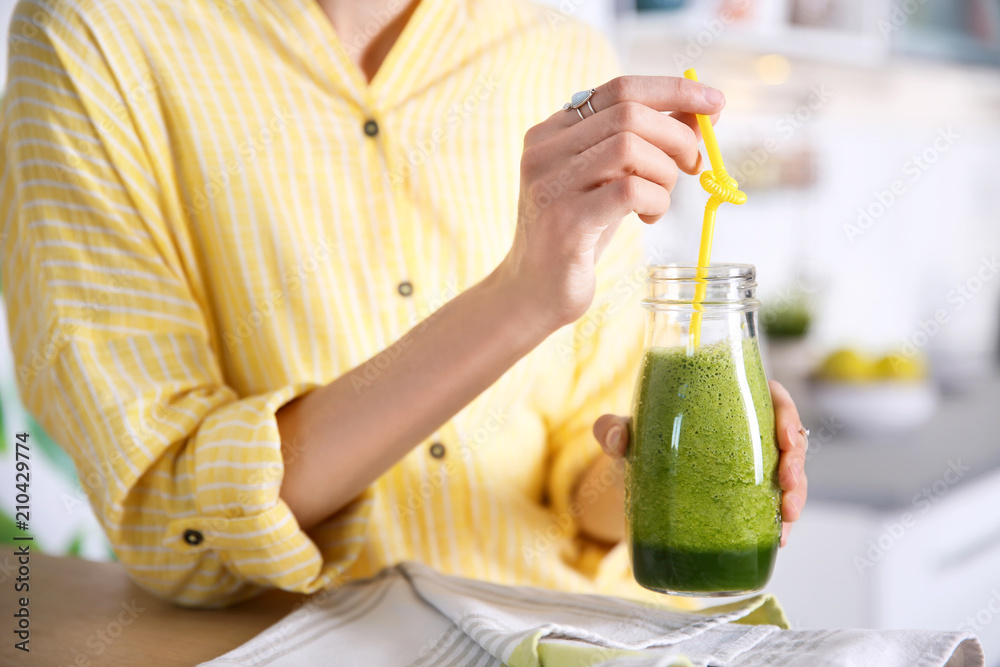 Young woman with bottle of healthy smoothie at table, closeup Young woman with bottle of healthy smoothie at table, closeup