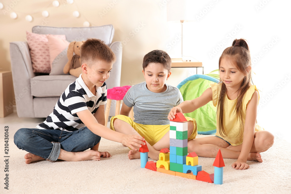 Cute little children playing with building blocks on floor, indoors