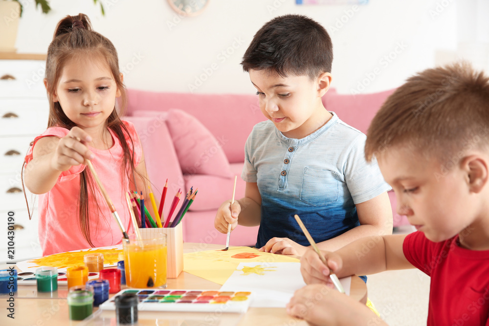 Cute little children painting at table in playing room Cute little children painting at table in playing room