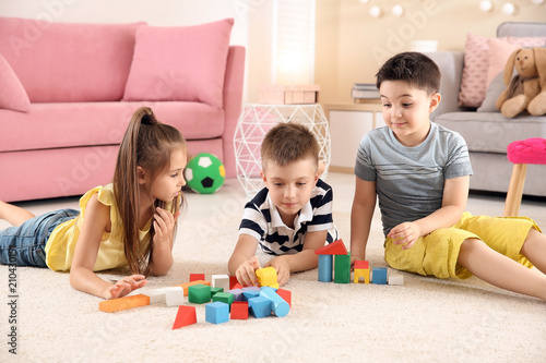 Cute little children playing with building blocks on floor  indoors