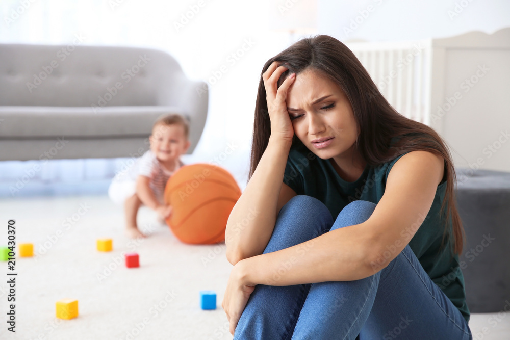 Obraz premium Young mother suffering from postnatal depression and little baby in room