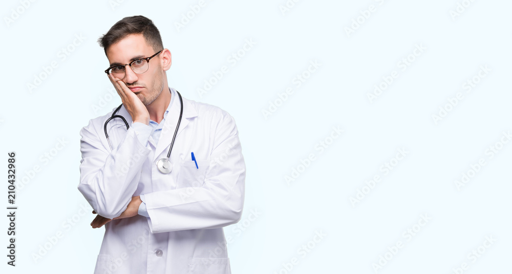 Handsome young doctor man thinking looking tired and bored with depression problems with crossed arms.