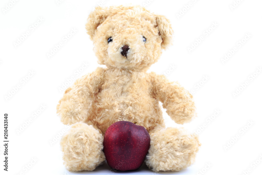 Obraz premium Teddy bear and red apple on a white background.