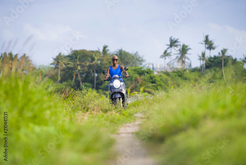 young attractive tourist afro American black woman riding motorbike happy in beautiful Asia countryside along green rice fields smiling free on her scooter