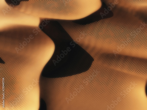 Aerial of sand dunes in low sunlight.