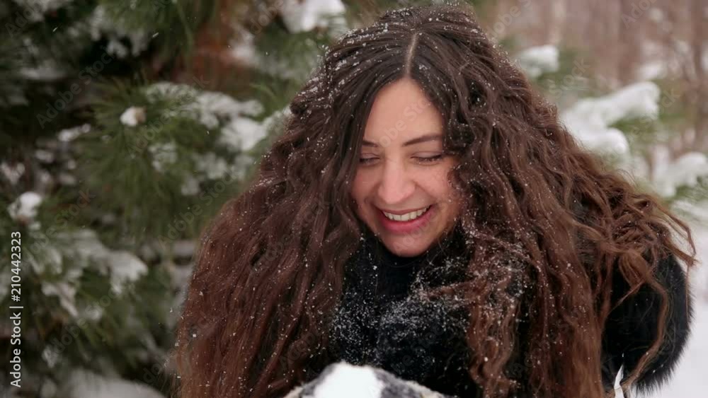 Cheerful pregnant girl blowing on snow in winter snow-covered park. Happy girl who is waiting for the child is walking and having fun in the winter park. Cheerful pregnant girl blowing on snow in winter snow-covered park. Happy girl who is waiting for the child is walking and having fun in the winter park.