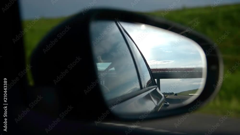 Shoot in rear-view mirror of car at road under evening sunset. Cynematic look loop footage. Shoot in rear-view mirror of car at road under evening sunset. Cynematic look loop footage.