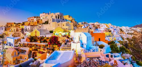 Panoramic view of Oia town, Santorini island, Greece at sunset. Traditional and famous white houses and churches  with blue domes over the Caldera, Aegean sea. photo