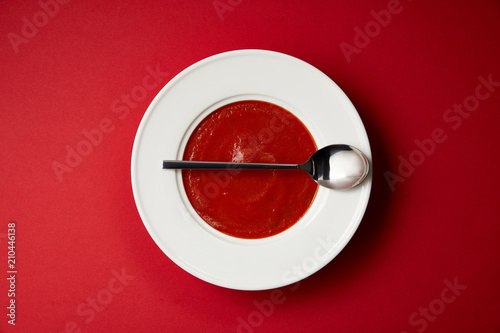 top view of tomato soup in plate and spoon on red table © LIGHTFIELD STUDIOS