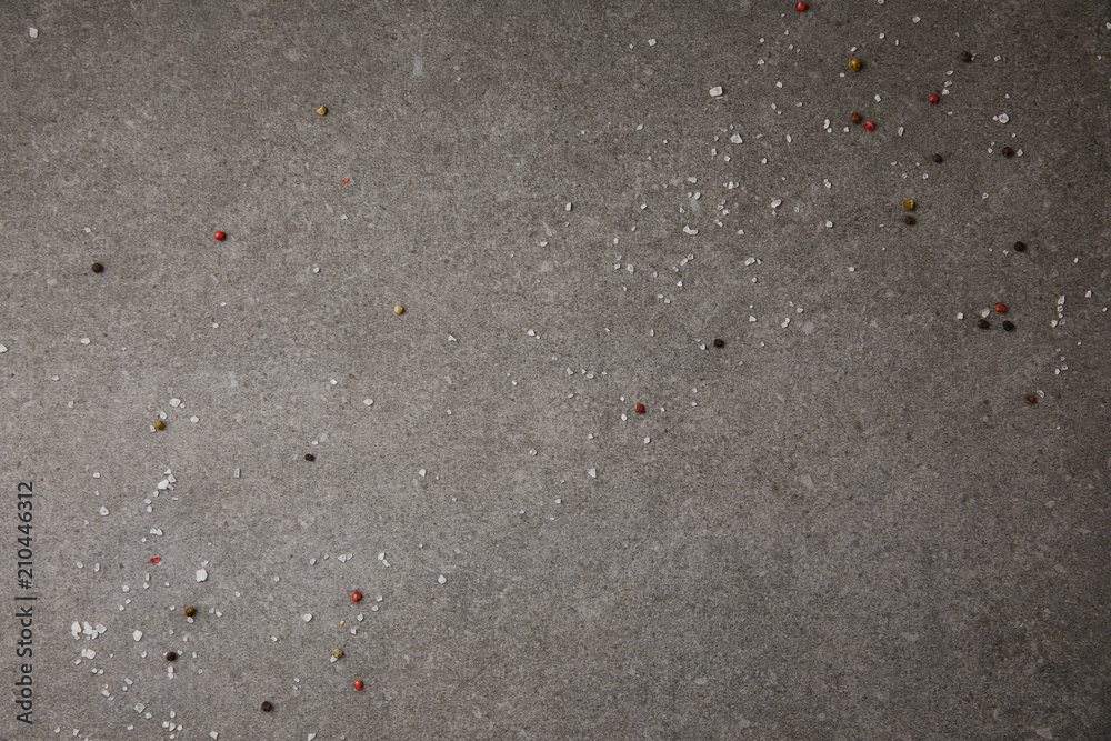 top view of scattered salt and pepper spices on grey table top view of scattered salt and pepper spices on grey table