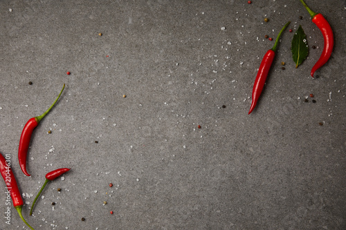 Fototapeta Naklejka Na Ścianę i Meble -  top view of chili peppers and scattered spices on grey table