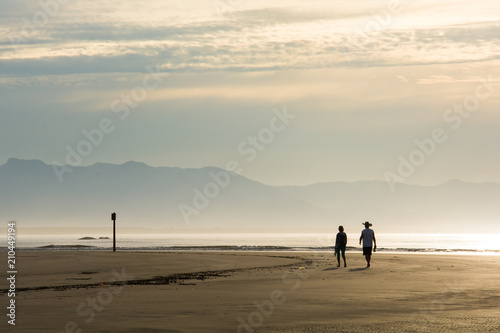 Casal caminhando na Praia da Enseada, ao amanhecer photo