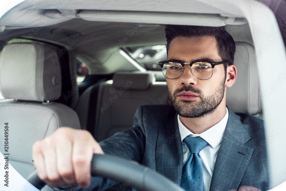 portrait of businessman in eyeglasses driving car alone