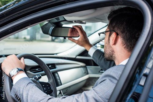 side view of businessman checking back view while driving car