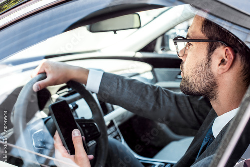 side view of businessman with smartphone driving car