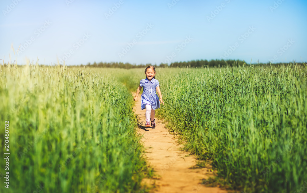 little girl in a dress runs across the field on a sunny day
