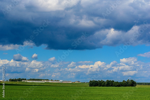 barn on a green field against a cloudy sky background © shymar27
