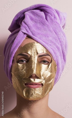 Joven mujer con mascara facial dorada.