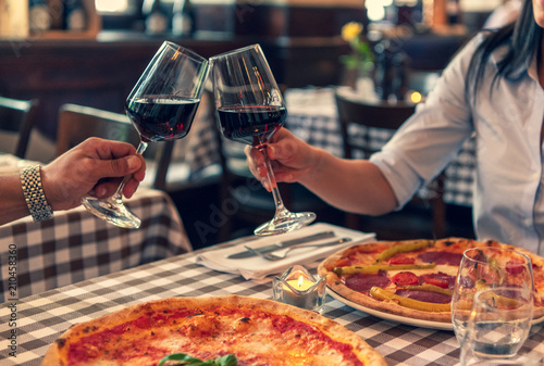 Verliebtes Paar stoßen auf Ihre Lieben an, halten Hand in einem Restaurant und essen Pizza und trinken Rotwein