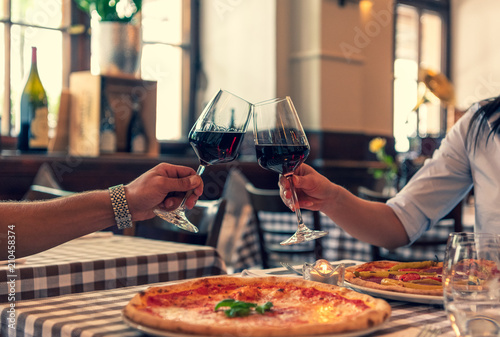 Verliebtes Paar sto  en auf Ihre Lieben an  halten Hand in einem Restaurant und essen Pizza und trinken Rotwein