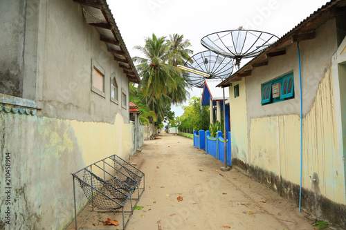 View of a streest on a local island, Maldives, Dhangethi. Traditional outdoor rope chairs. Poor environment and beautiful nature. Green palm trees on background.  photo