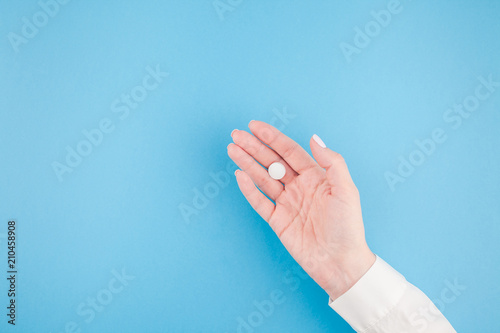 Female hand holding a white pill